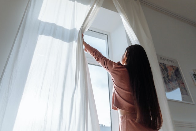 Person opening a white curtain